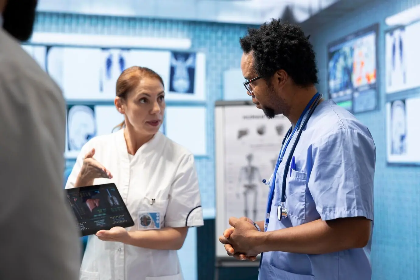 Врачи в кабинете обсуждают результаты рентгенографии и КТ для нового плана лечения.